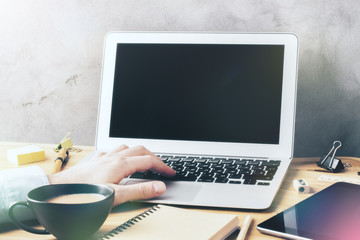 Fototapeta premium Man working with a laptop on a wooden table with a cup of coffee