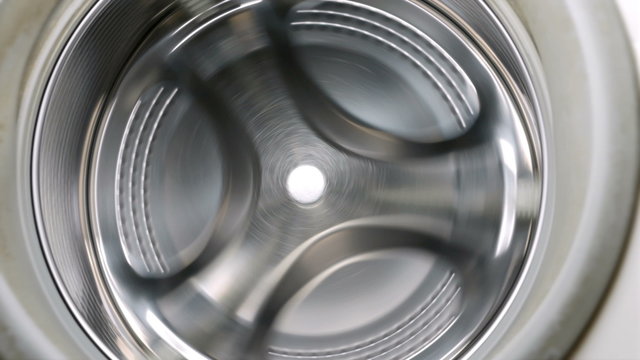Rotating empty washing or drying machine in a laundry. Household equipment and cleanliness hygiene housework concept. 4K UHD video footage.