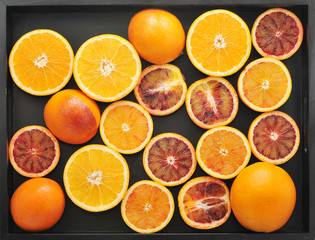 oranges whole and cut in half on a black tray. background from t
