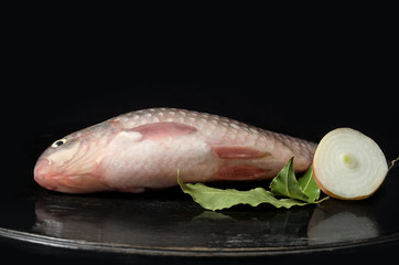 Raw fish on a black background and antique wooden surface.