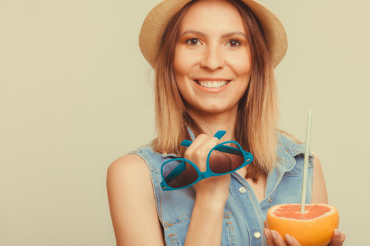 Happy woman in hat holds sunglasses and grapefruit