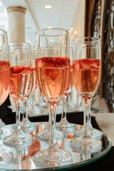 Festive champagne flutes filled with sparkling wine and floating strawberries romantic twinkling party lights