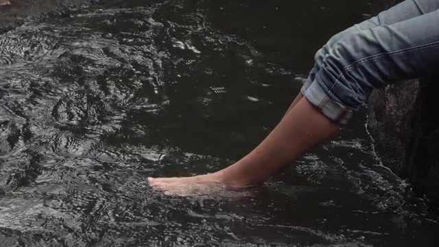Slow motion video of a  bare feet woman splashing and kicking her legs in the water in the jungle of  khao yai National park, thailand. Full Hd footage made at day.
