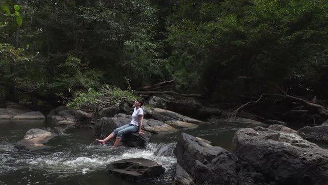 Slow motion video of a  bare feet woman splashing and kicking her legs in the water in the jungle of  khao yai National park, thailand. Full Hd footage made at day.
