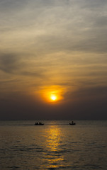 Fototapeta na wymiar Group of people riding banana boat into the sea with sunset