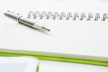 Open notebook with metallic ball pen and tablet