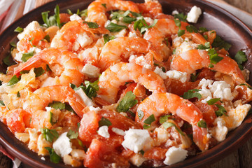 Saganaki prawns with feta cheese and tomatoes close-up. horizontal

