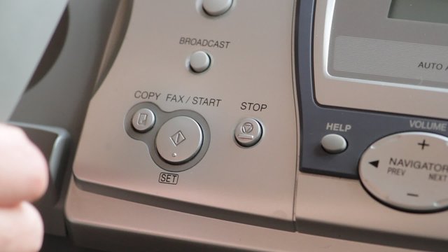 the hand presses the Fax button, close-up