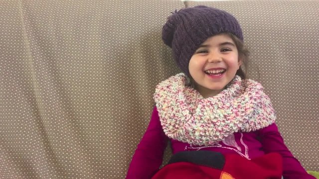 Happy smiling little girl sitting on the sofa