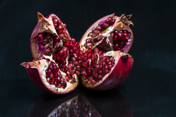 Broken Azerbaijani pomegranate on a black mirror table reflected on it