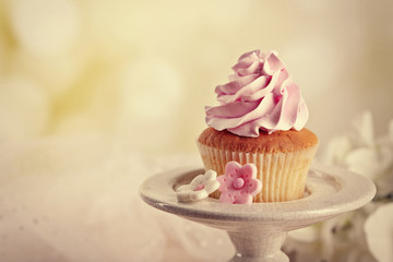Tasty cupcake on stand, on light background