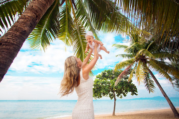 Young mother and cute baby playing on tropical beach 