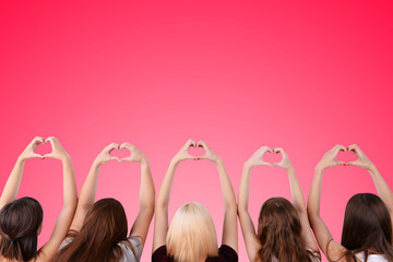 Obraz na płótnie Canvas Young people makes hearts using fingers on pink background