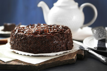 Tasty chocolate cake on color wooden background