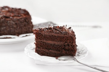 Sliced chocolate cake on wooden table, on light background