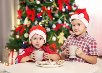 Two cute small brothers eating cookies on Christmas decoration background