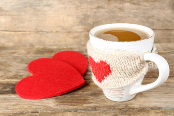 Cup of coffee with red felt hearts on wooden background, close up