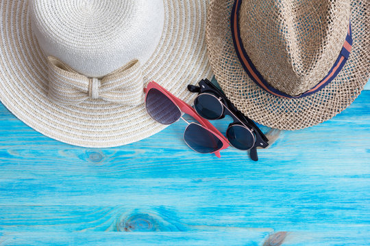 Summer hats  and sunglasses on blue wooden background