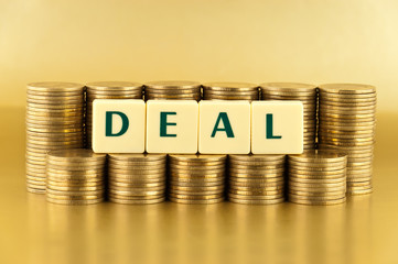 the letters DEAL with stacks of coins