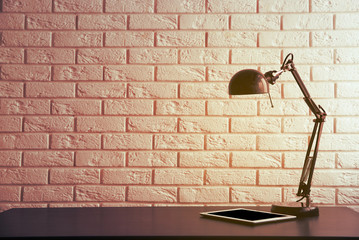 Fototapeta na wymiar Office lamp on the desk on brick wall background