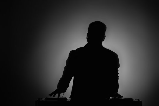 DJ playing music at mixer in dark