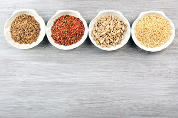 Different kinds of seeds in bowl on wooden table