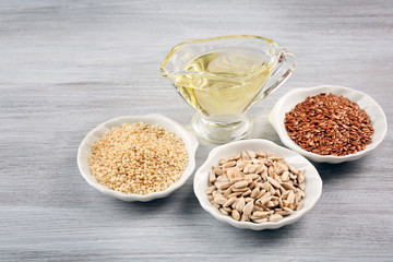 Different kinds of seeds with oil on wooden table