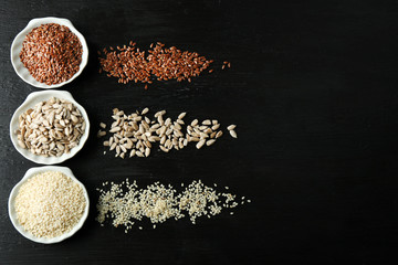 Flax, sesame and sunflower seeds on wooden table