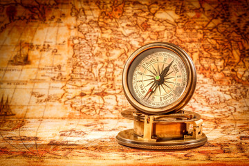 Vintage compass lies on an ancient world map.