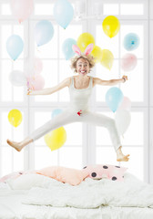 Fooled jumping on the bed, active morning! Positive emotions! Happy life. Blond jumping on the bed with his legs apart side Sporting exercise on the bed. Healthy lifestyle.Crazy Rabbit