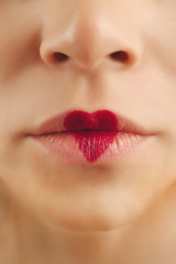 Obraz premium Sexy lips with cherry-coloured heart shape paint, closeup