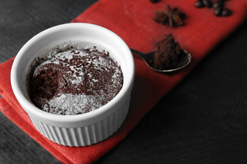 Chocolate fondant cake in cup on wooden table closeup