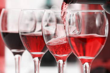 Red wine pouring into glasses, closeup