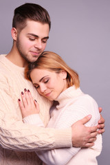 Young couple in love embracing on grey background