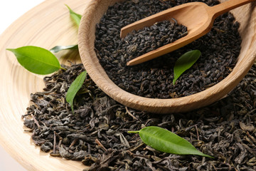 Dry tea with green leaves in wooden utensil, close up