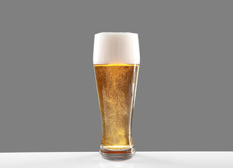 Glass of lager beer on grey background