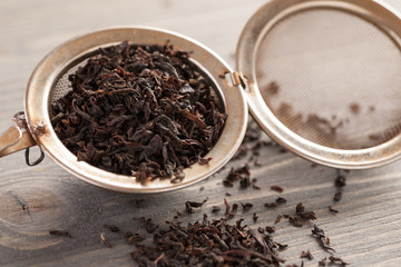 Black tea in metal strainer on a wooden table
