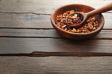 Herbal tea in a round bowl with a spoon on wooden table, close up