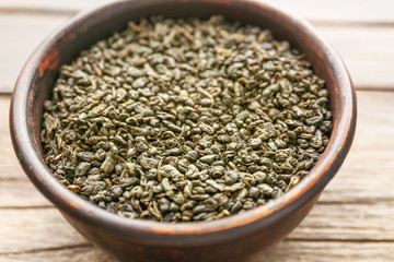 Green tea in a round bowl on wooden table, close up