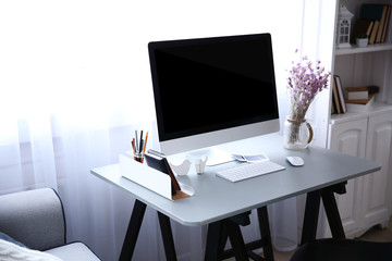 Modern interior. Comfortable workplace. Wooden table with beautiful bouquet of flowers and computer on it.