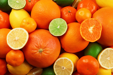 A heap of mixed citrus fruit including   lemons, limes, grapefruit and tangerines with slices, top view