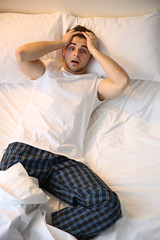 Young man lying in bed at home