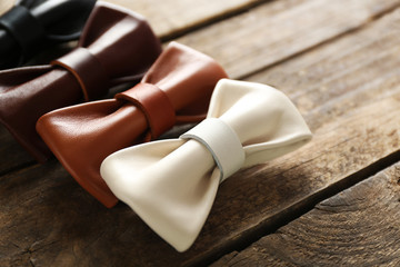 A set of leather bow ties lined on a brown wooden background