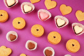 Tasty cookies and candies for Valentines Day on purple background