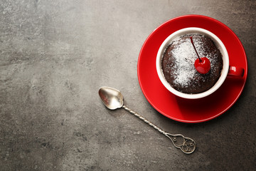 Chocolate cake in a red mug  with a cherry on top, top view