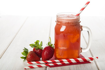 Batido, smoothie o zumo de fresa natural fresco sobre mesa de madera y fondo blanco en mason jar.