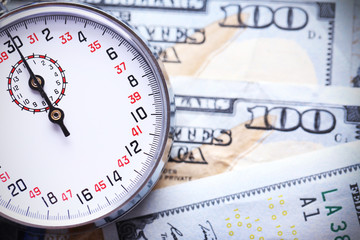 Naklejka premium Stopwatch on dollar banknotes, close up. Time is money concept