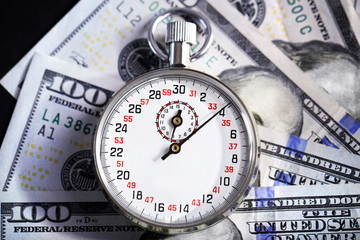 Stopwatch with dollar banknotes on black background. Time is money concept