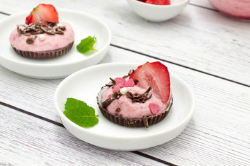 Strawberry mousse in chocolate cups on a white plate.