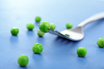Fototapeta premium Fork with green peas on blue background